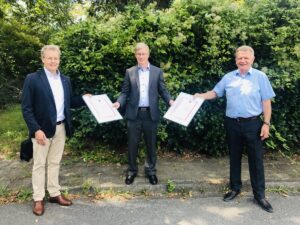 Ulrich Stahl (Vorstandsvorsitzender) und Axel Grimm (Geschäftsführer) überreichen Michael Muerköster die Urkunden über langjährige Mitgliedschaft der Unternehmen Danfoss GmbH und Danfoss/DEVI.