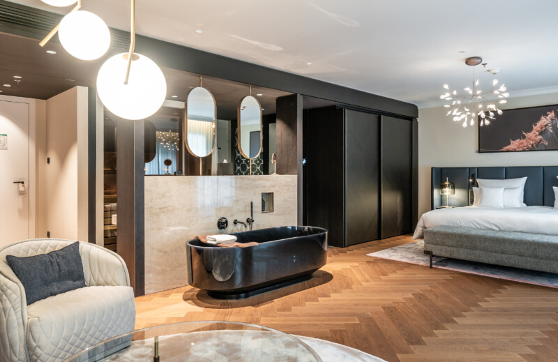 Die Spa-Suite verbindet Wohnen und Wellness in einem offenen Raumkonzept – mit freistehender Badewanne, angrenzender Sauna und warmen Naturmaterialien.